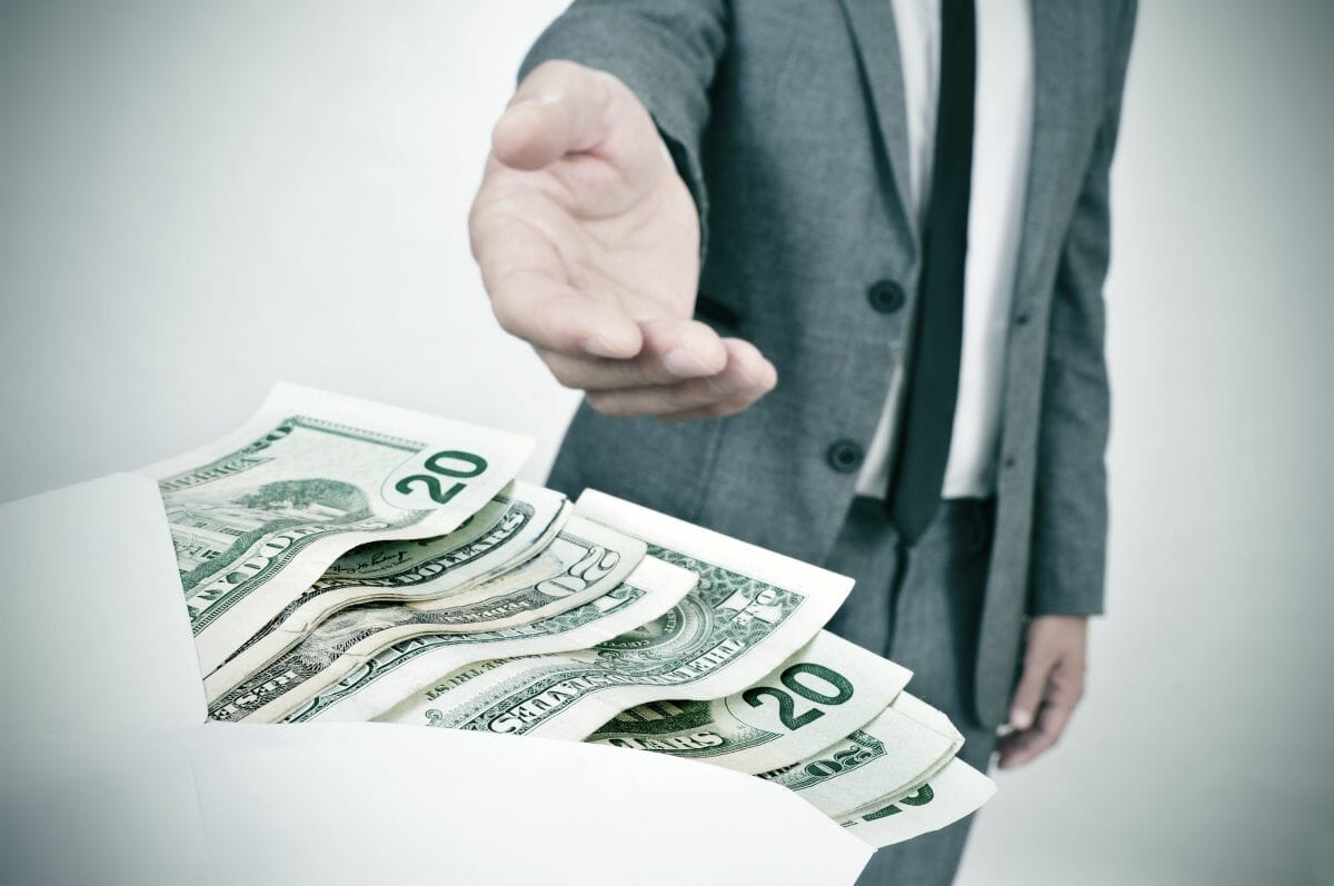 person taking envelope full of money | Are Bonuses Taxed Differently Than Commissions? | Tax Rate on Bonuses | tax rate on bonuses | tax on bonuses