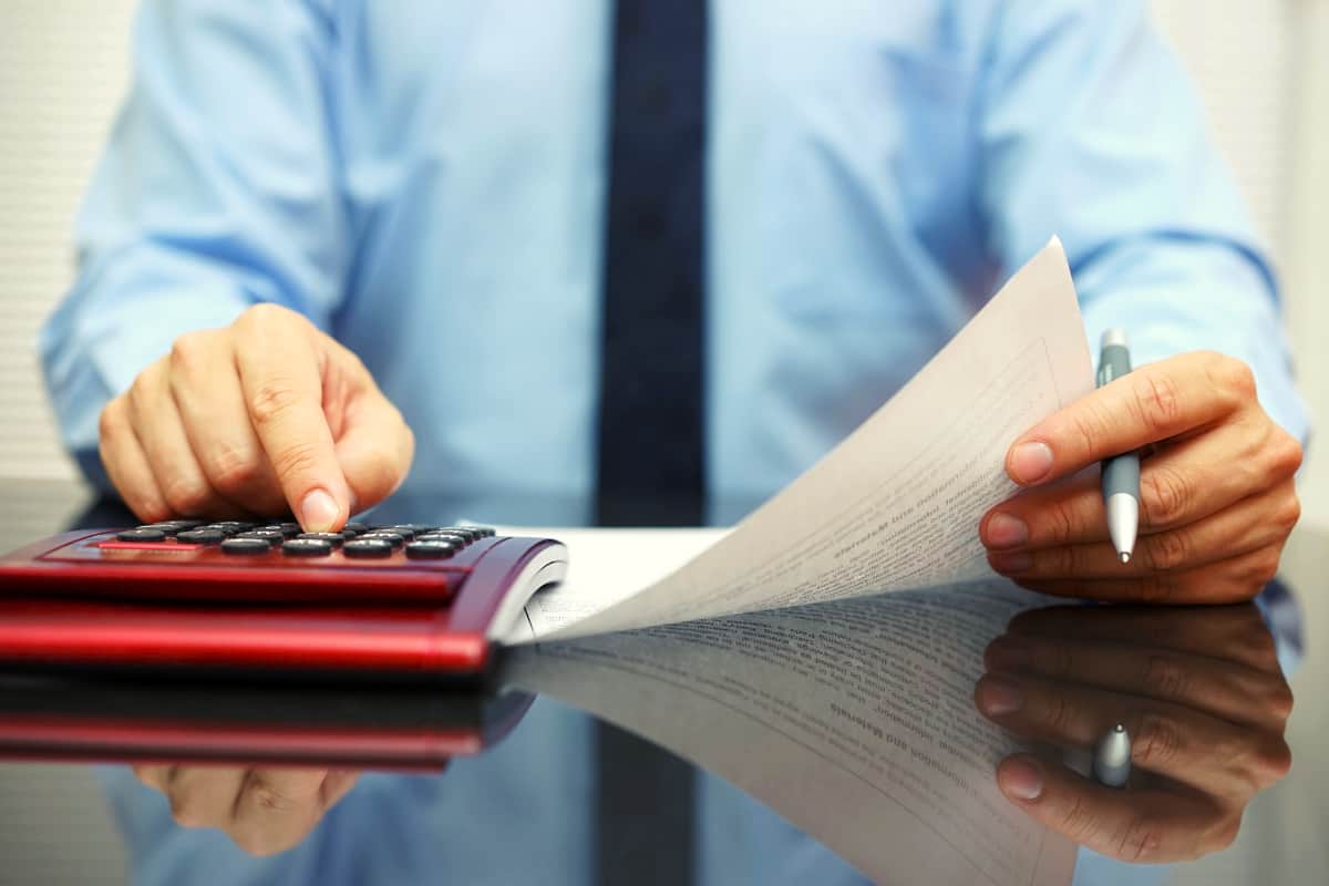 man reading document and using calculator | The Master List of All Types of Tax Deductions | types of tax deductions | common tax deductions