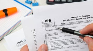 Featured | Man holding US tax form W-9 | Basics Of The IRS W9 Form