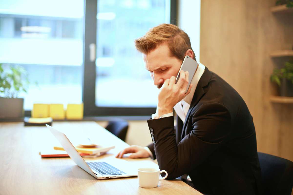 man in an office using his phone and laptop | IRS Letter 4464C | What It Means