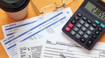 1040A tax form with payslips and a calculator | What Is IRS Tax Form 1040a? | what is 1040a | 1040a instructions | Featured