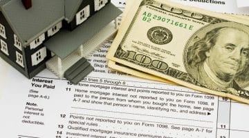 Featured | A model house sitting on tax papers | Mortgage Tax Deduction Options You Should Know About