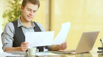 Feature | attentive businessman working comparing paper documents | Filing As Head Of Household | FAQs