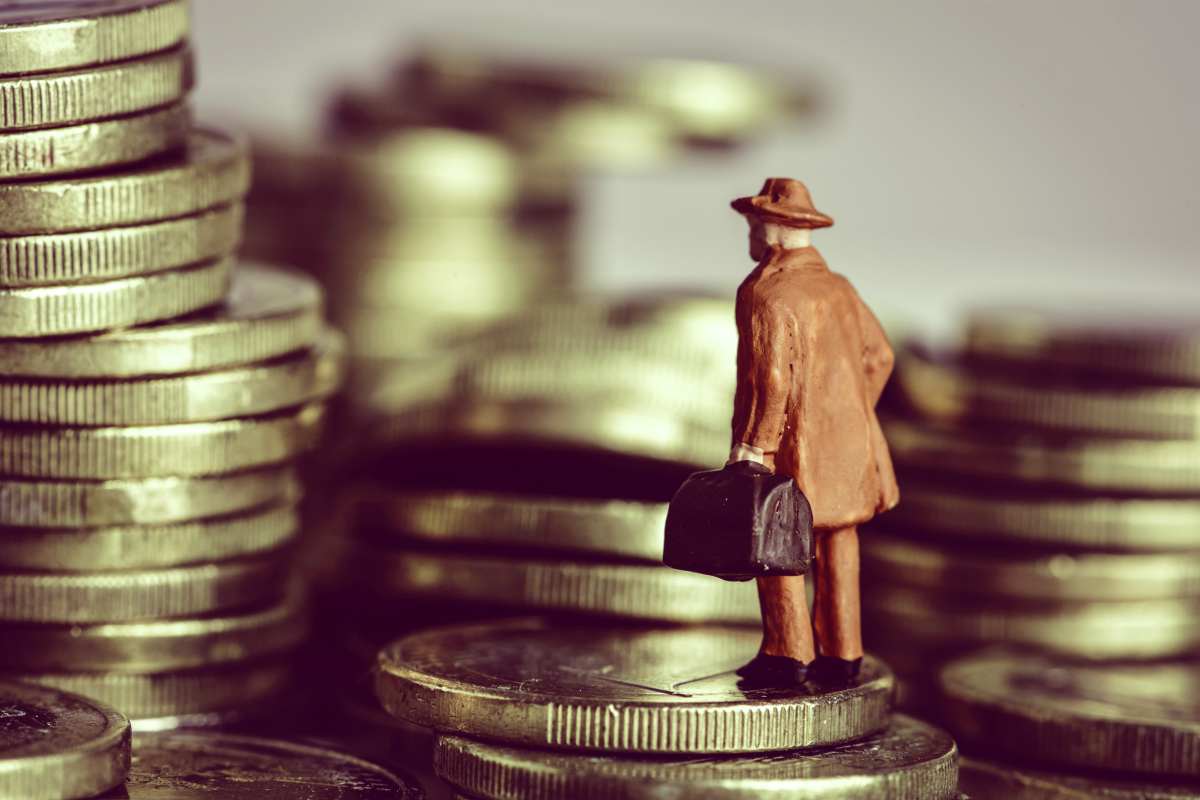miniature man on coins | The Differences Between Tax Avoidance and Tax Evasion