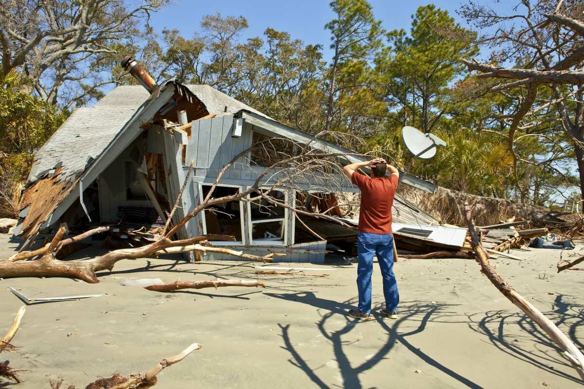 man grieving over house destroyed by flood | Tax Relief For Natural Disaster Victims | disaster tax relief