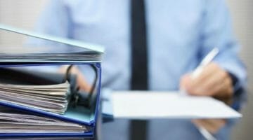 Feature | businessman signing papers | Tips On Filing Back Taxes | How to file back taxes