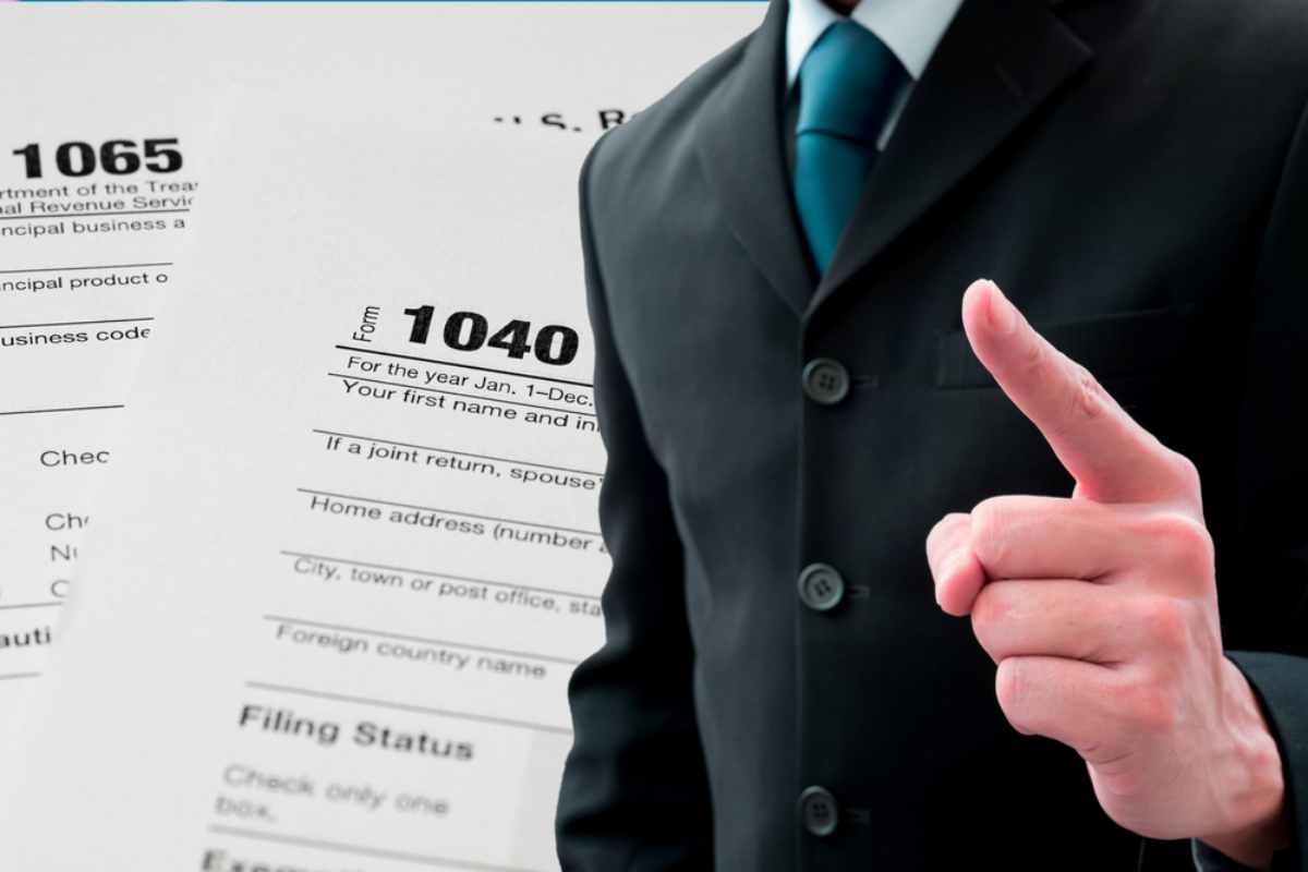 Man pointing his finger in tax form background | Things NOT To Say To The IRS If You Owe Back Taxes