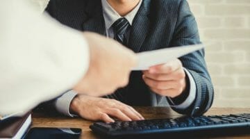 Feature | businessman passing document | A Step-By-Step Guide To Settling IRS Tax Debt | irs tax debt