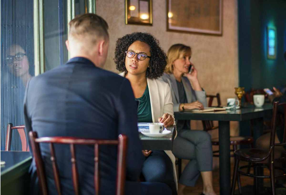 Man and Woman talking about tax documents at cafe | Things NOT To Say To The IRS If You Owe Back Taxes