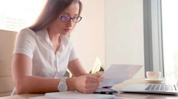 Feature | serious worried businesswoman attentively reading letter | IRS Letter: What to Do If You Get An IRS Collection Notice | irs collection