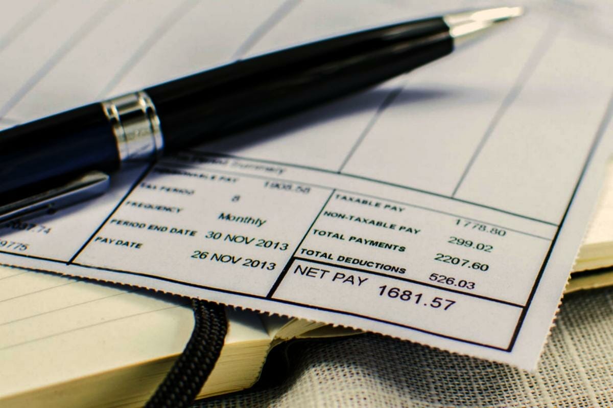 wage slip on notepad black pen | Wage Garnishment: What To Do If The IRS Garnishes Your Wages | garnished wages