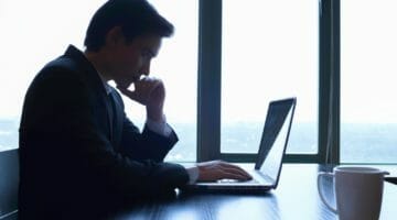 Feature | serious businessman looking at laptop | The 3 Types Of IRS Offer In Compromise And Their Eligibility Requirements