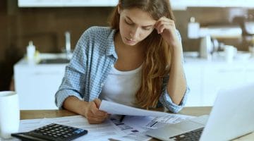 Featured | worried woman looking at documents | How To Request For An IRS Hardship Payment Extension | how to request an extension for taxes
