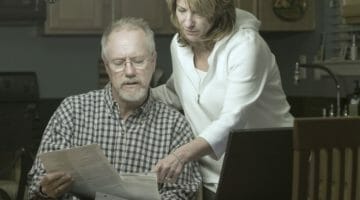 couple reading financial statement | How To Remove A Tax Lien Notice From Your Credit Report | how to remove tax lien from credit report | how to remove state tax lien from credit report | Featured