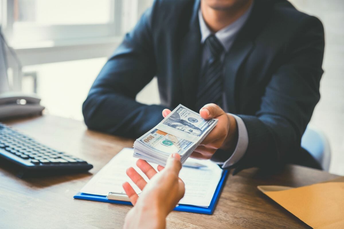 businessman giving money to his co-worker | How To Get A Tax Deduction Due To Bad Business Debt | bad debt deduction | business bad debt deduction